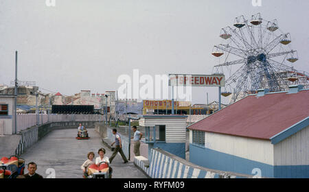 Années 1970, à l'extérieur à un champ de foire, les parents et les enfants faisant l'attraction's speedway ride sur une voie en béton, England, UK. Banque D'Images