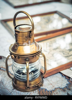 Ancienne lanterne bateau brassy se dresse sur une carte de la mer près de photos avec l'image de mer noeuds Banque D'Images