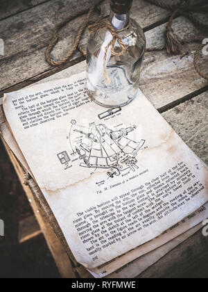 Vintage still life with sextant photo dans un vieux livre et bouteille en verre vide avec une corde sur de fond de bois. Le livre décrit la technique de Banque D'Images