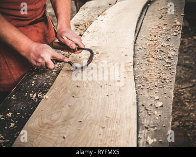 Carpenter à l'époque médiévale vêtements en coton avec un Drawknife ou le dessin d'un couteau ou d'attirer et de rasage rasoir couteau sont des outils à ciseler sur planche de bois Banque D'Images