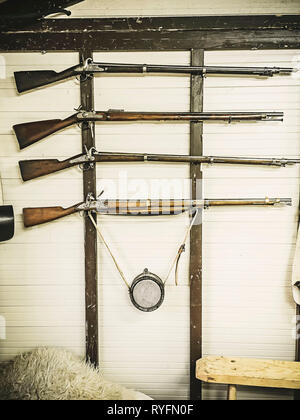 Ancien service rifles de la fiole de poudre militaire accroché sur la paroi en bois. Le fusil sur un mur blanc Banque D'Images