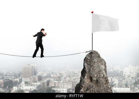 Businessman walking et équilibre sur corde vers drapeau blanc de sommet de montagne avec cityscape background Banque D'Images