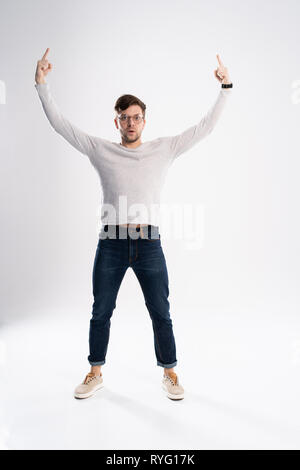 Bel homme portant des lunettes étonné et souriant à la caméra tout en présentant à part isolé sur blanc. Banque D'Images