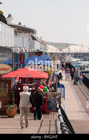 Les gens qui marchent le long de la promenade dans le port de plaisance de Brighton, Sussex, Angleterre. Banque D'Images