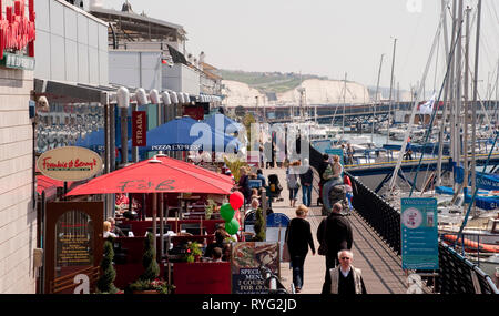 Les gens qui marchent le long de la promenade dans le port de plaisance de Brighton, Sussex, Angleterre. Banque D'Images