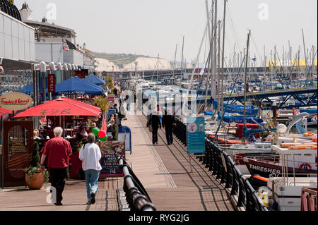 Les gens qui marchent le long de la promenade dans le port de plaisance de Brighton, Sussex, Angleterre. Banque D'Images