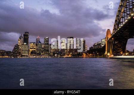 Le crépuscule sur le quartier du centre-ville de Sydney skyline par le port de Sydney, et le célèbre pont, en Australie plus grande ville. Banque D'Images