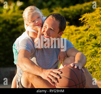 Smiling père assis sur une allée avec sa jeune fille. Banque D'Images