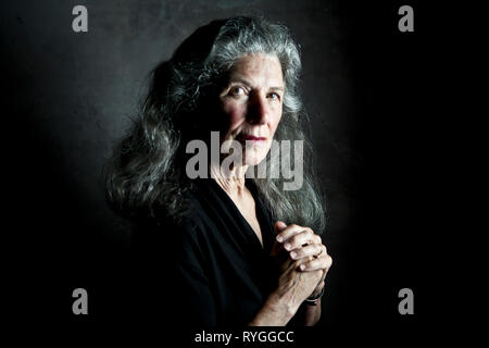 Portrait d'une femme plus âgée avec de longs cheveux gris de profil avec ses mains jointes devant elle Banque D'Images