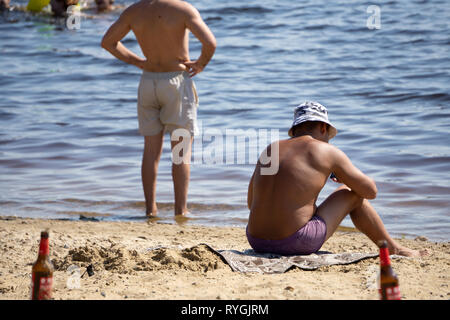 Un jeune homme macho avec une barbe courte et godet hat est assis sur la plage contre le fond de la mer près de Punta Cana, République Dominicaine Banque D'Images