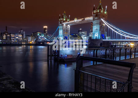 Tower Bridge, Londres, Angleterre. 13 mars 2019. Un plan d'ensemble du célèbre pont sur la Tamise de nuit avec des bâtiments et l'eau calme lumineux Banque D'Images