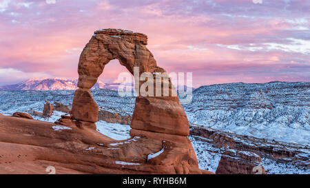 Un coucher de soleil colorés s'allume Montagnes La Sal derrière Delicate Arch iconique en février 2019 après une tempête de neige à Arches National Park, Moab, Utah. Banque D'Images