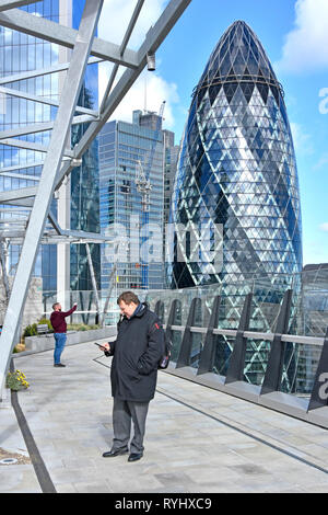 Gherkin London city office building à partir de la plate-forme d'observation au jardin sur le toit de la Cour Fen hommes hiver visiteurs & téléphone mobile Fenchurch Street England UK Banque D'Images