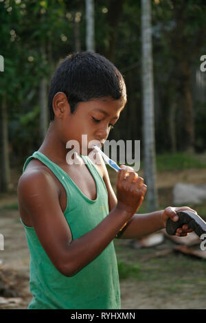 Le BANGLADESH Boy de minorités tribales Garo se brosser les dents, Haluaghat, Mymensingh région photo par Sean Sprague Banque D'Images