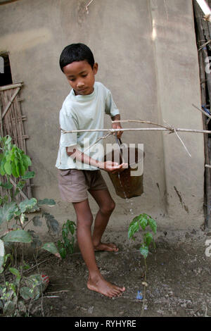 Le BANGLADESH Garçon du Garo de minorités tribales l'arrosage des plantes dans le jardin de ses parents, Haluaghat, Mymensingh région photo par Sean Sprague Banque D'Images