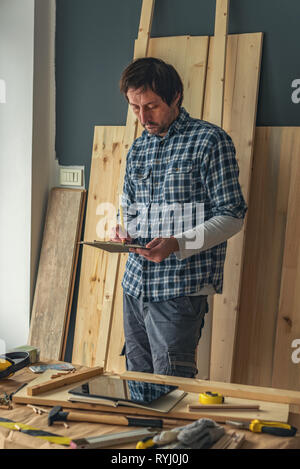 Carpenter à écrire des notes sur papier bloc-notes de presse-papiers dans la petite entreprise atelier de menuiserie Banque D'Images