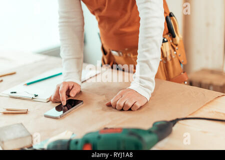 Female carpenter using smartphone, Close up of hands, selective focus Banque D'Images