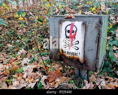 Ancienne piscine boîtier électrique avec une haute tension signer dans les feuilles Banque D'Images