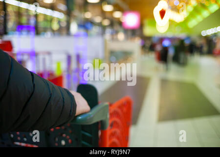 Arrière-plan flou du supermarché aux couleurs vives. Un homme faire du shopping. Les mains des hommes avec panier close-up. Le caissier, gueues au magasin. Vente temps concept. Banque D'Images