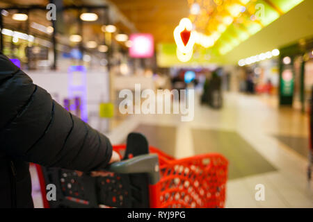 Arrière-plan flou du supermarché aux couleurs vives. Un homme faire du shopping. Les mains des hommes avec panier close-up. Le caissier, gueues au magasin. Vente temps concept. Banque D'Images