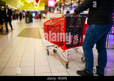 Arrière-plan flou du supermarché aux couleurs vives. Un homme faire du shopping. Les mains des hommes avec panier close-up. Le caissier, gueues au magasin. Vente temps concept. Banque D'Images