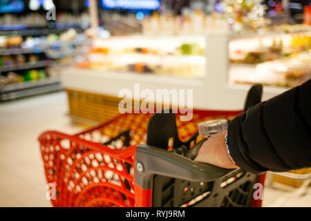 Arrière-plan flou du supermarché aux couleurs vives. Un homme faire du shopping. Les mains des hommes avec panier close-up. Le caissier, gueues au magasin. Vente temps concept. Banque D'Images