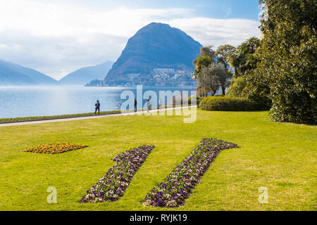 Lugano, Suisse - 10 mars 2019 : Belle vue pittoresque de Ciani Park sur le lac de Lugano et les Alpes Suisses avec les gens Banque D'Images