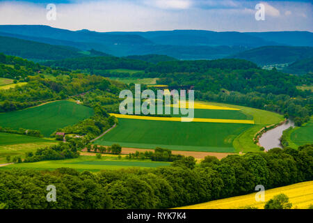 Belle vue panoramique sur la vallée de la Werra paysage. La rivière Werra s'écoule à travers les champs de canola cultivées et un pont de chemin de fer, entouré d'une forêt... Banque D'Images