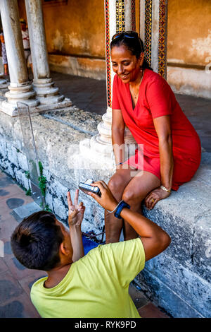 Jeune garçon de 12 ans de prendre une photo de sa mère dans le cloître de la cathédrale de Monreale, Sicile (Italie). Banque D'Images