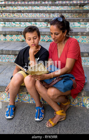 La mère et le fils a guide book sur un escalier à Caltagirone, en Sicile (Italie). Banque D'Images