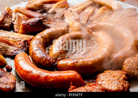De délicieuses saucisses, bacon et juteux burgers de petits faits de viandes hachées sont frémir sur barbecue. Banque D'Images