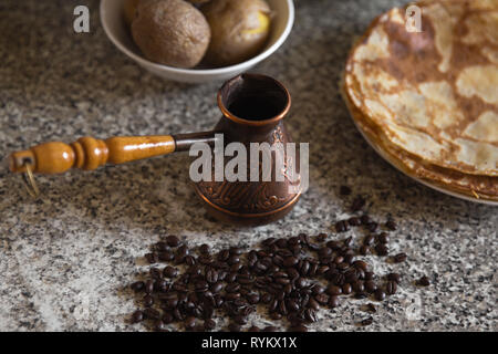 Cezve avec des grains de café et crêpes de pommes de terre bouillies dans l'arrière-plan Banque D'Images