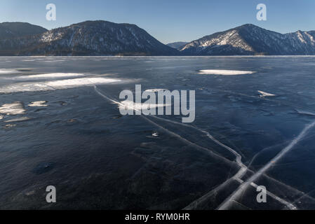 Belle vue hivernale du lac Teletskoye congelé avec des fissures dans la glace sur la toile de fond de montagnes et de ciel bleu. L'Altaï, en Russie. Banque D'Images