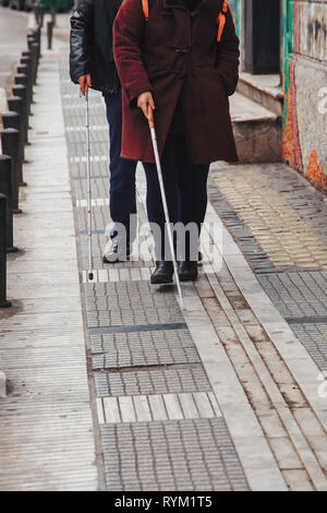 Blind man and woman walking on the street en utilisant une canne blanche Banque D'Images