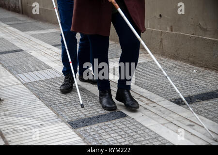 Blind man and woman walking on the street en utilisant une canne blanche Banque D'Images