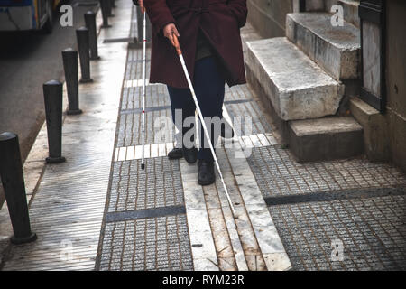 Blind man and woman walking on the street en utilisant une canne blanche Banque D'Images