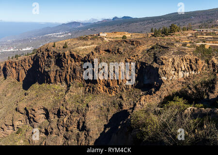 Voir dans le Barranco de Guaria et une ferme finca à distance au-dessus de la falaise, et les falaises de Los Gigantes sur l'horizon, à partir de Las Fuentes Banque D'Images