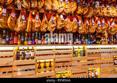 Des centaines de jambons espagnols Jamón Serrano suspendus au-dessus des étagères de vin au Mercado Central à Valence, en Espagne Banque D'Images
