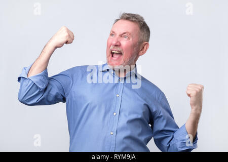 Happy senior homme fort, soulevant ses poings fermés dans hourra geste, triomphant Banque D'Images