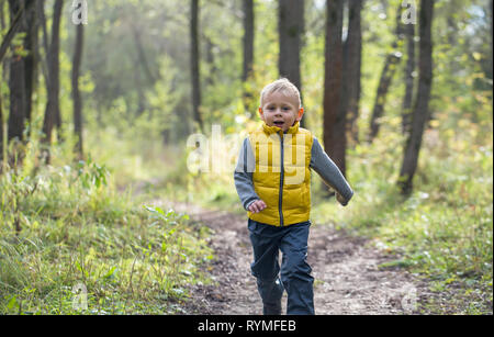 Jeune garçon court le long d'un chemin forestier sur une journée ensoleillée d'été Banque D'Images