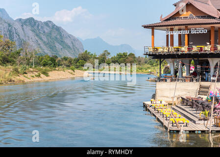 Vang Vieng, Laos - 28 décembre 2018 : un restaurant au bord de la rivière, la rivière Nam Song et la montagne en arrière-plan. Banque D'Images