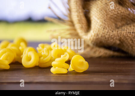 Lot de pâtes crues funghetto variété avec un sac de jute avec champ de blé vert Banque D'Images