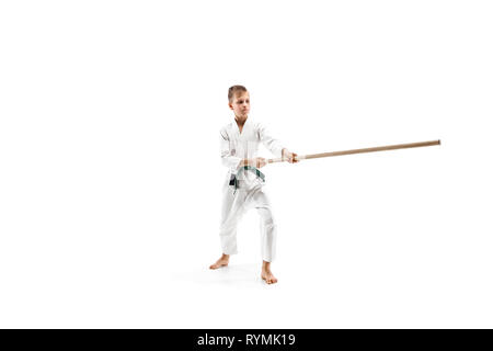 Teen boy combat avec sabre en bois à l'aïkido en école d'arts martiaux. Style de vie sain et de sport concept. Fightrer en kimono blanc sur fond blanc. L'homme en uniforme de karaté. Banque D'Images