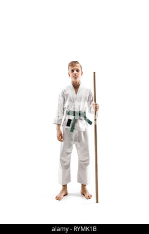 Teen boy combat avec sabre en bois à l'aïkido en école d'arts martiaux. Style de vie sain et de sport concept. Fightrer en kimono blanc sur fond blanc. L'homme en uniforme de karaté. Banque D'Images