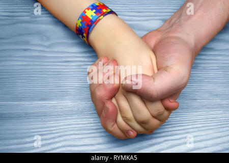 Photo de la sensibilisation à l'autisme. Père holding hand son enfant autiste Banque D'Images