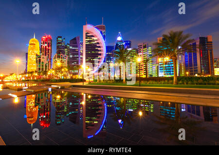 West Bay Doha des tours illuminées par nuit se reflétant dans l'eau du parc en centre-ville. Les gratte-ciel modernes de toits de Doha, au Qatar, au Moyen-Orient Banque D'Images