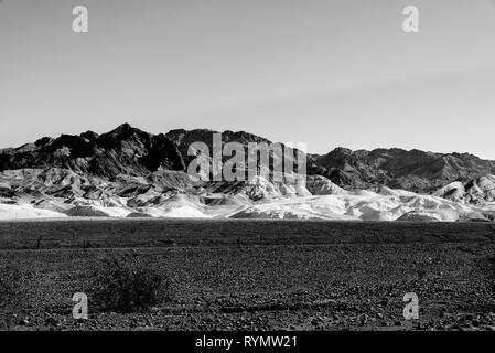 Noir et blanc, la Death Valley en Californie où la végétation est clairsemée, dark champs rocailleux fait place au blanc des collines et montagnes du désert aride. Banque D'Images