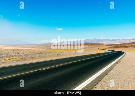 L'autoroute du Désert qui traverse des terres arides sous ciel bleu. Banque D'Images