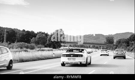 Schiltach, Allemagne - Jun 10, 2018 : image en noir et blanc de l'autoroute allemande de luxe avec Mustang décapotable cabriolet voiture conduite rapide sur la route de campagne sur une journée ensoleillée avec des montagnes en arrière-plan de la Forêt-Noire Banque D'Images