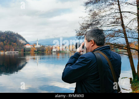 L'homme à prendre des photos de l'Église et le lac de Bled en Slovénie. Voyages en Europe Banque D'Images